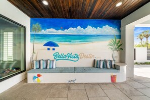A beach-themed mural, a curved bench with cushions, and a logo. - *Bella Vista Luxe*Pool & Hot Tub*Golf Cart*Theater (Miramar Beach)