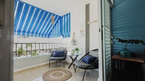 Een balkon met twee stoelen, een kleine tafel en een bloempot.