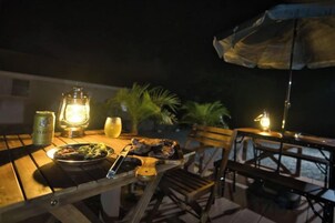 Un espacio de comedor al aire libre con una mesa, sillas, un farol y una sombrilla.
