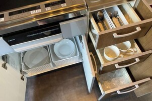 Una cocina con lavavajillas integrado, microondas y un cajón con utensilios.