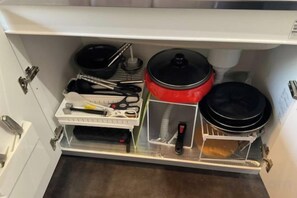 A kitchen cabinet with cookware and utensils. - Racine Yakushima (Yakushima)