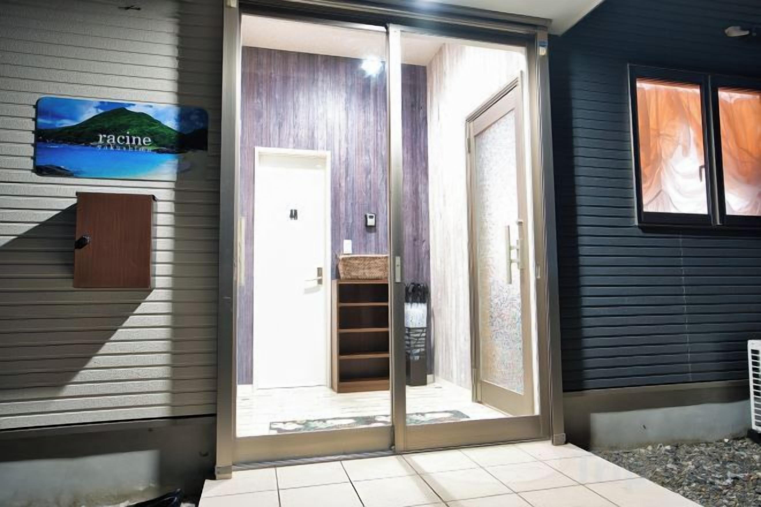 A sliding glass door leading to a room with a white door and a shelf with a basket.