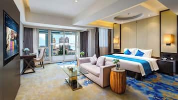 Una habitación de hotel con cama, sofá, mesa de centro de vidrio y vistas a la ciudad.