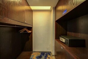 Una habitación pequeña y cerrada con armarios de madera, un perchero y una estantería con un dispositivo.