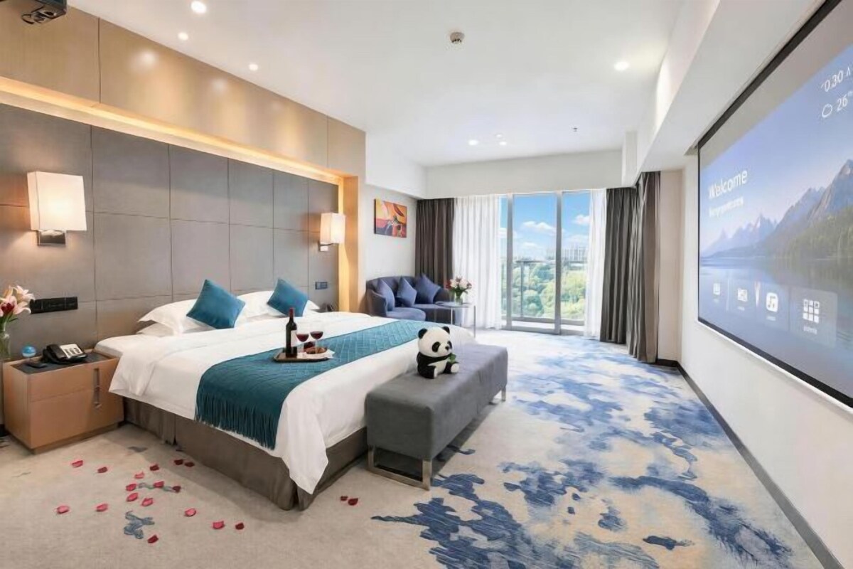 Une chambre d’hôtel moderne avec un grand lit, un bureau, une chaise et une grande fenêtre.