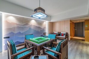 A room with a dining table, chairs, a hanging light fixture, and a wall with a mountain design. - LiSheng Yijia Hotel (Chengdu)