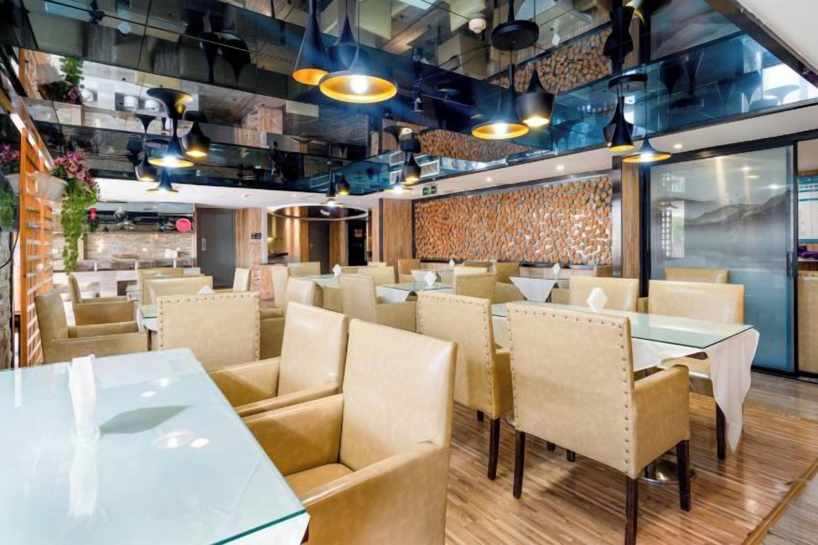 A modern restaurant interior with high ceilings, exposed ductwork, and contemporary lighting fixtures.