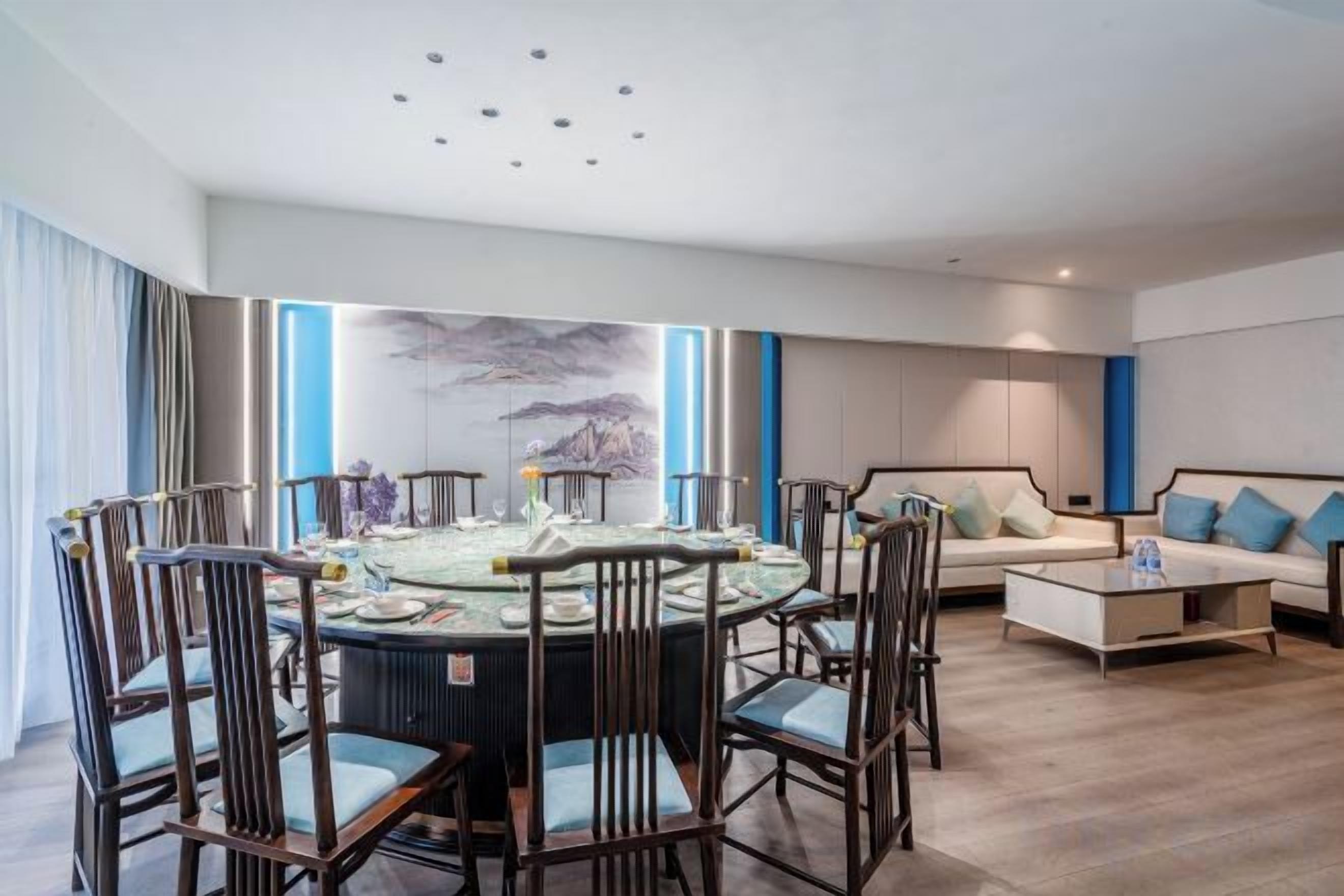 Una habitación de hotel moderna con una mesa redonda de comedor, sillas, un sofá y una mesita de centro.