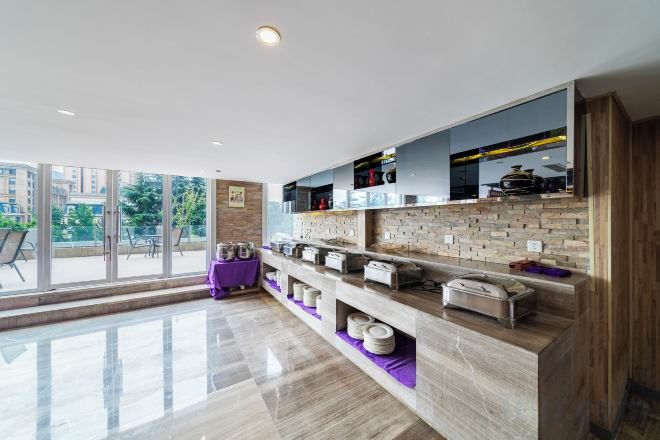 A modern kitchen with a marble countertop, built-in appliances, and a large window offering a view of the outdoors.