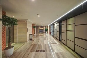 A hotel corridor with a polished floor, potted plants, and a modern interior design. - LiSheng Yijia Hotel (Chengdu)