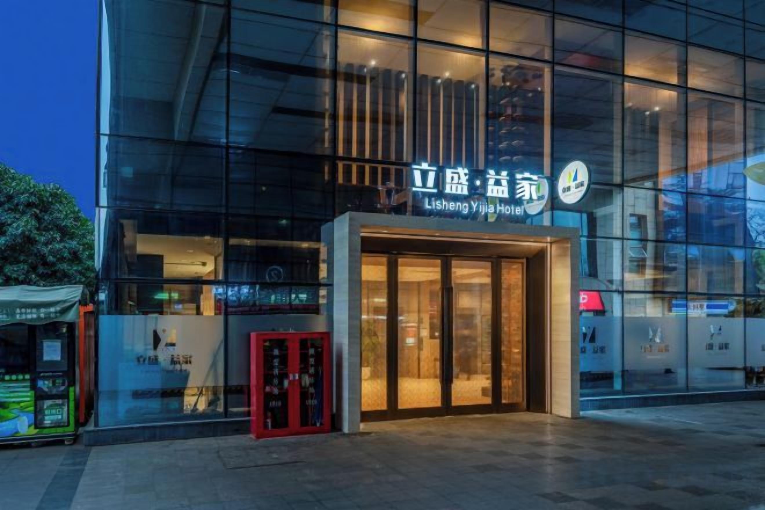Un edificio moderno con fachada de vidrio y un letrero que dice 'Lisheng Yijia Hotel'.