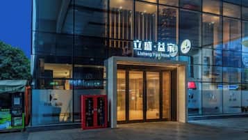 Un edificio moderno con fachada de vidrio y un letrero que dice 'Lisheng Yijia Hotel'.