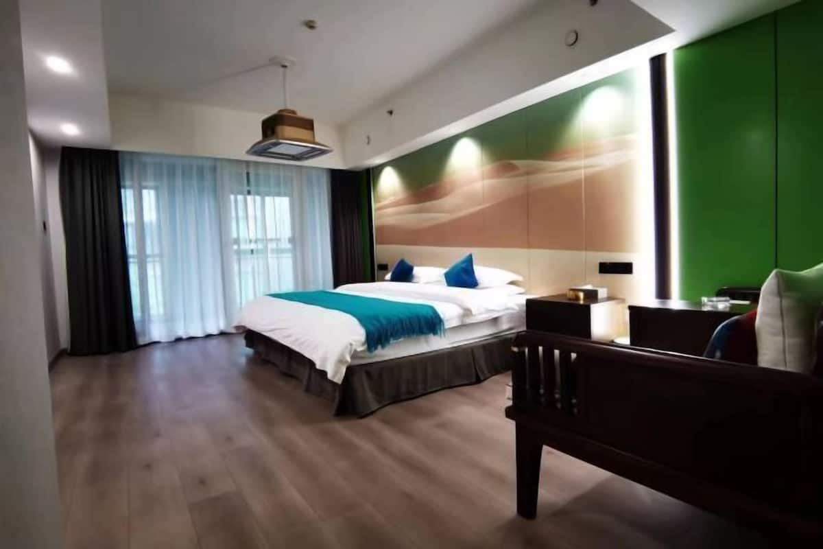 A hotel room with a large bed, a desk, and a green accent wall.