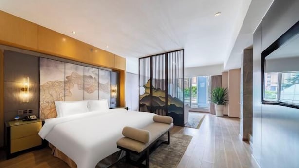 A modern hotel room with a large bed, bedside tables, a bench, a decorative wall, and a large window. - LiSheng Yijia Hotel (Chengdu)