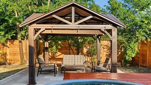 Un patio techado con piscina, terraza de madera y mobiliario exterior.