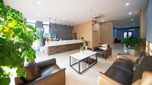 A modern hotel lobby with a reception desk, seating area, and potted plants. - Haining Stranger Shanghua Hotel (Haining)
