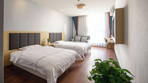 A modern hotel room with two beds, a desk, a chair, a TV, and a large window with curtains. - Haining Stranger Shanghua Hotel (Haining)