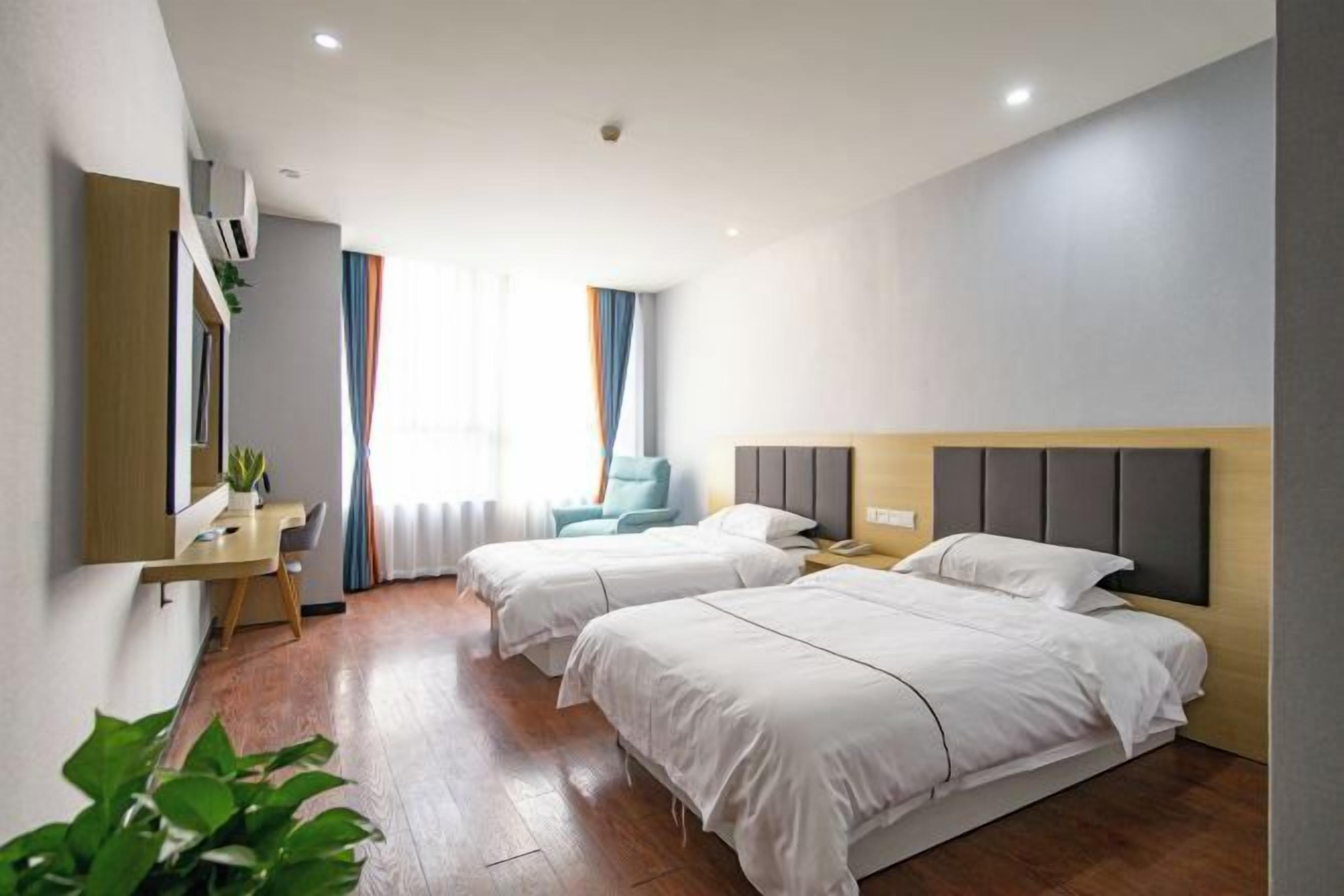 A hotel room with two beds, a desk, and a chair.