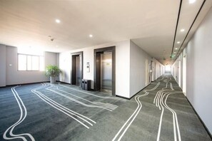 A long hallway with carpeted flooring and doors on both sides. - Haining Stranger Shanghua Hotel (Haining)