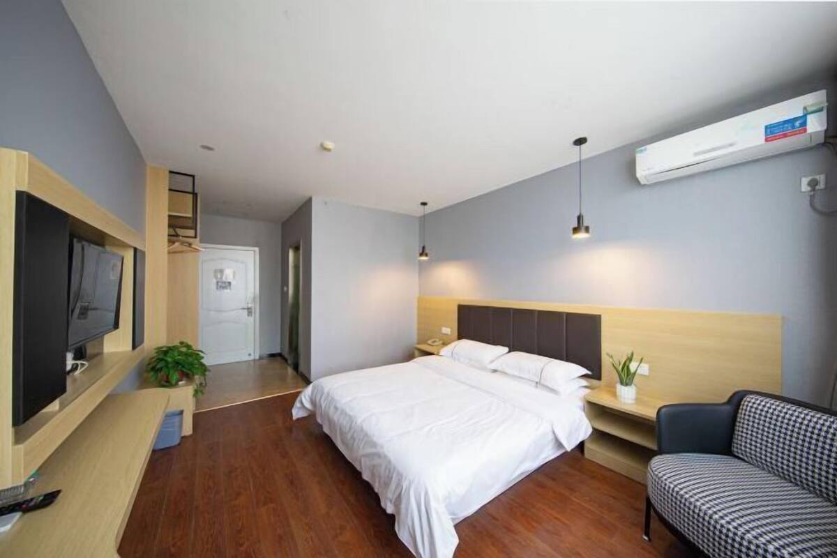 A hotel room with a bed, bedside table, TV, and a seating area.