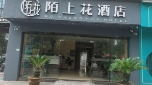 A hotel entrance with a glass door, potted plants, and a sign in both Chinese and English. - Haining Stranger Shanghua Hotel (Haining)