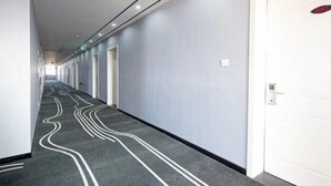 A long, narrow hallway with a patterned carpet, white doors, and a ceiling with recessed lighting. - Haining Stranger Shanghua Hotel (Haining)