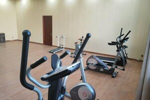 Un gimnasio con bicicletas estáticas, cintas de correr y una máquina de remo.