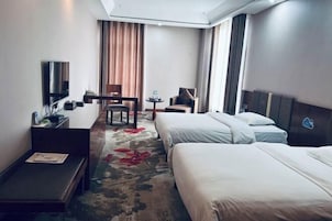 Una habitación de hotel con una cama, un escritorio, una silla, una mesita y un televisor.