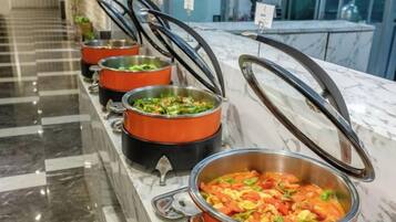 Un buffet proposant une variété de plats présentés dans des récipients de service en métal.