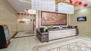 A reception area with a marble reception desk, a large framed artwork, and a television on the wall. - Shuang Long Hotel (Gaotai)