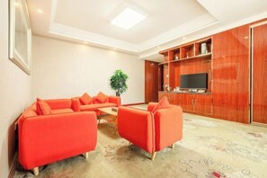 Een moderne woonkamer met een zithoek, een flatscreen televisie en houten kasten.