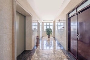 A hallway with a marble floor, a potted plant, and a door on the right. - Shuang Long Hotel (Gaotai)