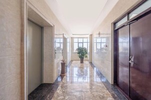 Un pasillo con piso de mármol, una planta en maceta y una puerta a la derecha.