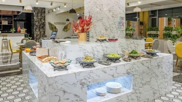 A marble reception desk with a variety of food items and a small display of plates. - Shuang Long Hotel (Gaotai)