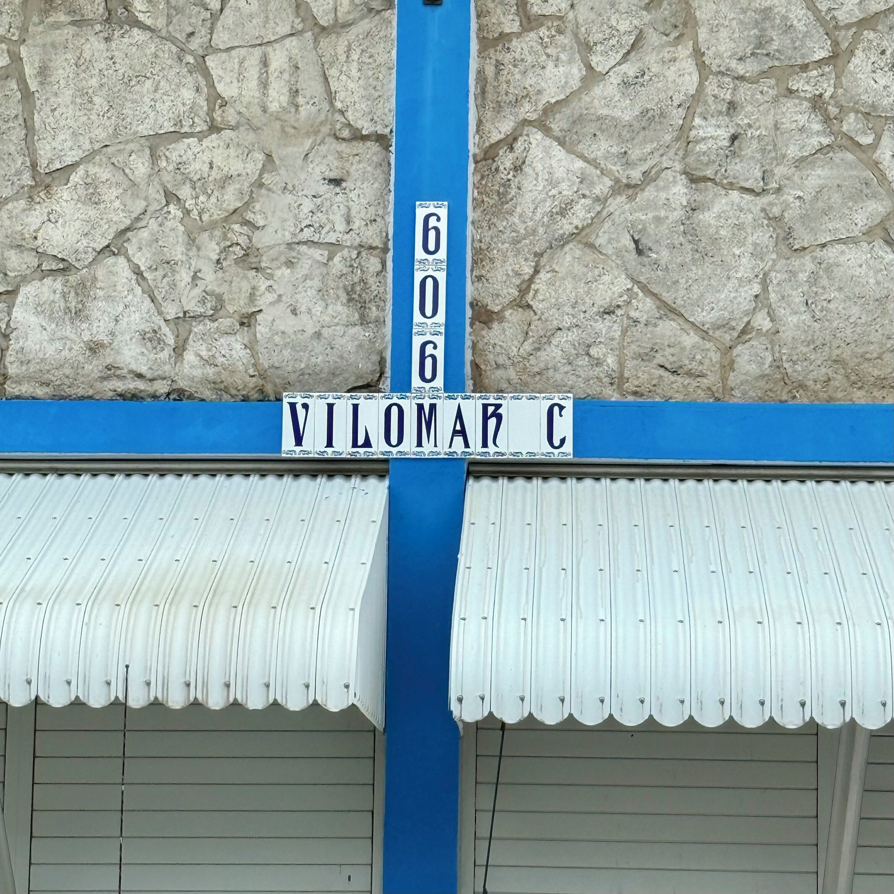 A street sign with the number 606 and the name "VILOMAR C" on a blue background.