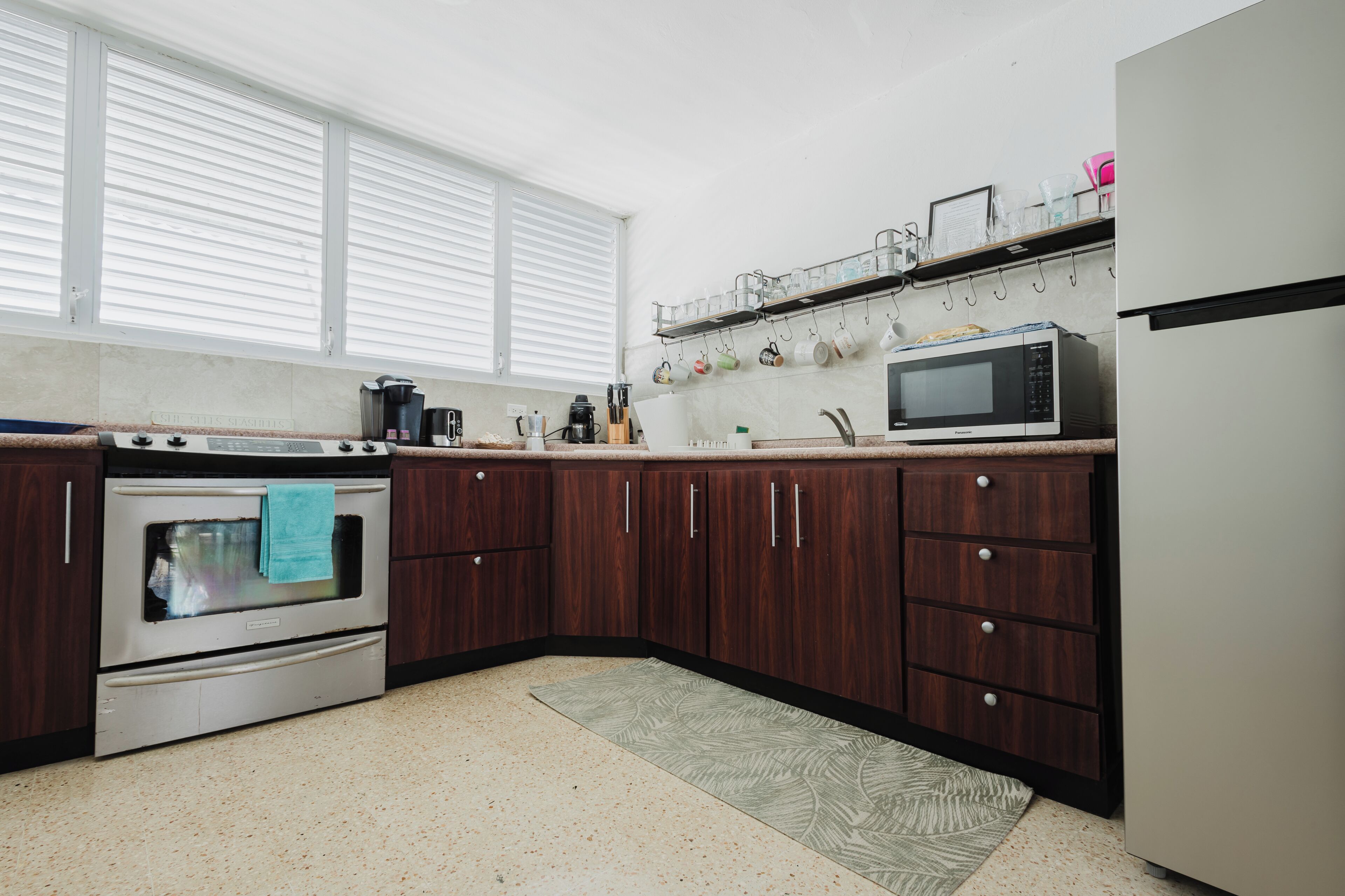 Eine Küche mit dunklen Holzausbau, einem Edelstahlbackofen, einer Mikrowelle und einem Kühlschrank.