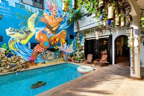 An indoor swimming pool with a mural of sea creatures, surrounded by potted plants and wooden chairs. - 6BR Boutique Hotel in Punta Sur (Isla Mujeres)