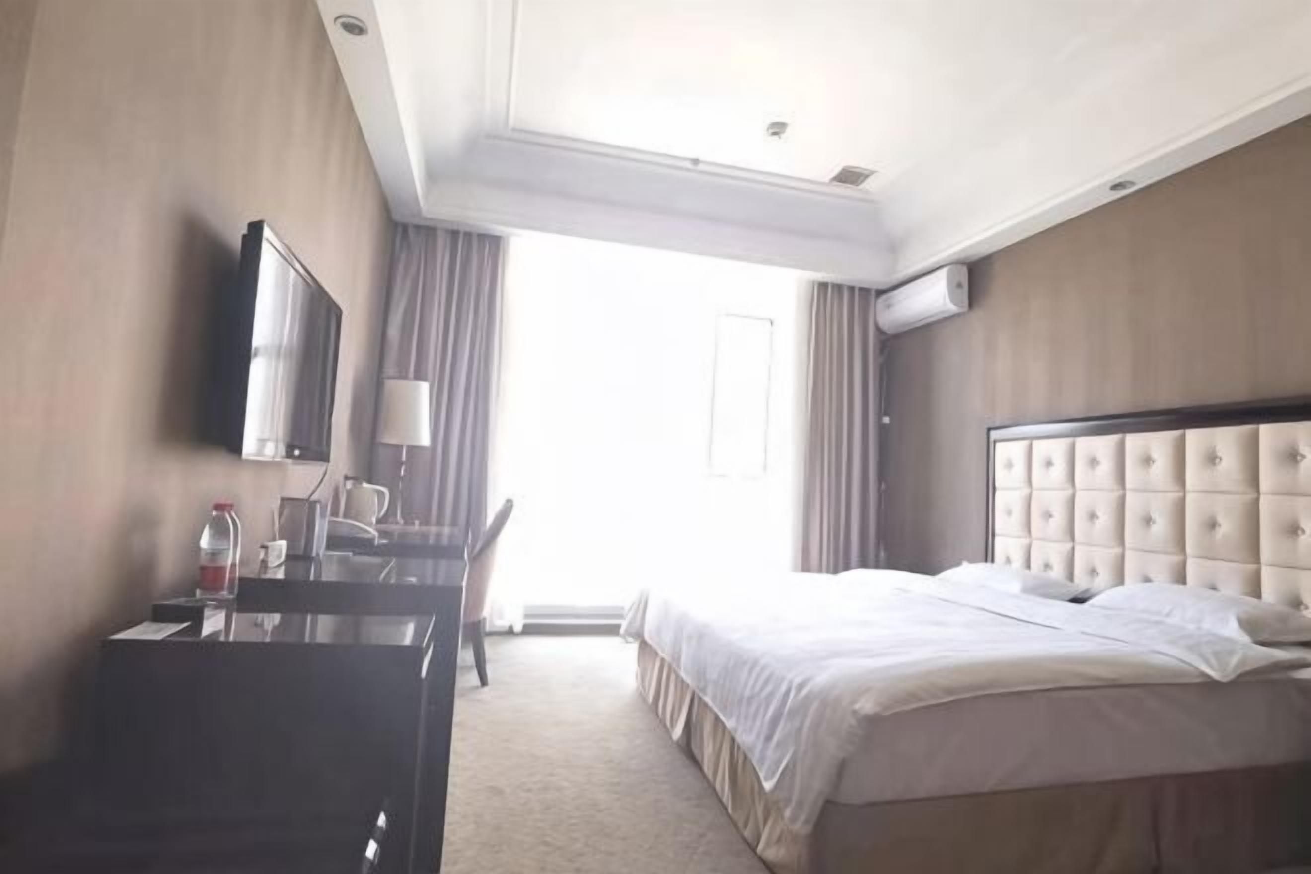 Una habitación de hotel con una cama, un escritorio, una silla, un televisor y una ventana.