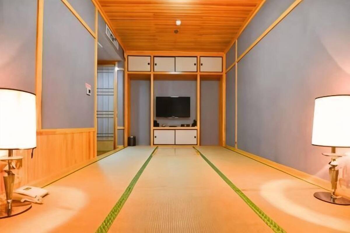 Ein Zimmer mit Fernseher, Holzboden und Tatami-Böden.
