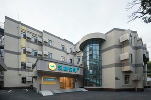 A building with a curved glass facade, a sign with Chinese characters, and a staircase leading to the entrance. - HanTing Express Hotel (Shanghai Xinzhuang Subway Station) (Shanghai)