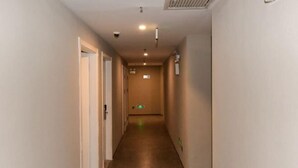 A narrow, well-lit hallway with a tiled floor, leading to a door at the end.