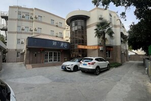 A multi-story building with a parking area, a storefront, and a staircase leading to an upper level.