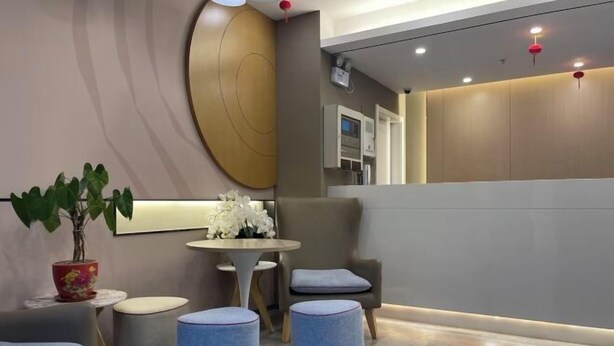 A modern reception area with a round table, seating, and a potted plant.