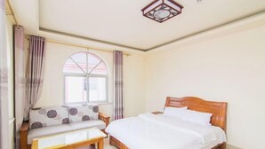 Une chambre à coucher avec un lit, un banc, une fenêtre et des rideaux.