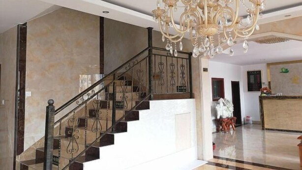 Un magnifique escalier orné d’un lustre, des murs en marbre et un espace d’accueil.