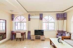 Una sala de estar con televisor, una mesa de centro, un sofá y un comedor con mesa y sillas.