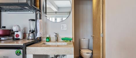 A compact kitchenette with a microwave, coffee maker, and a rice cooker.