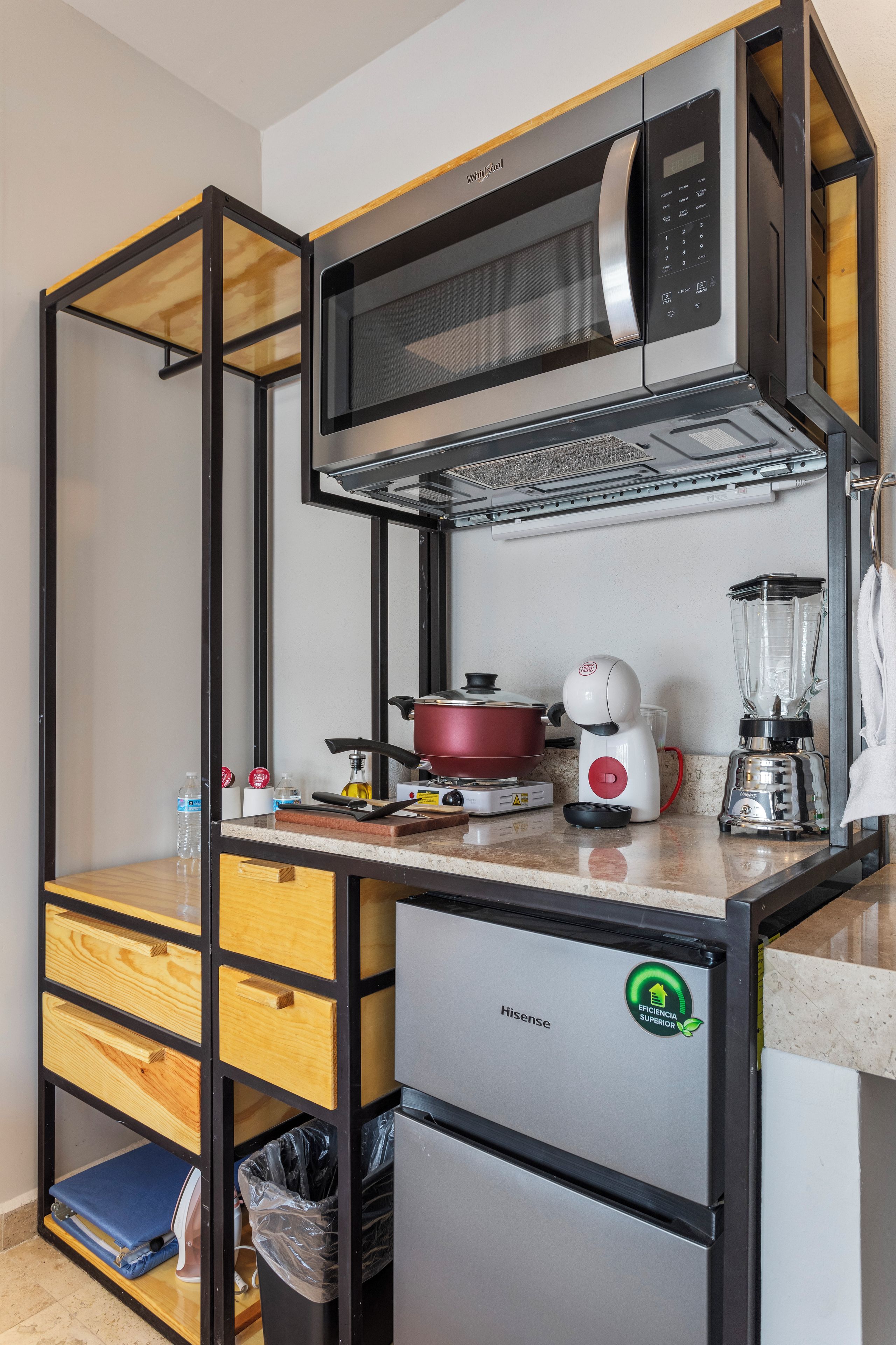 A compact kitchenette with a microwave, a small refrigerator, a blender, and a stove.