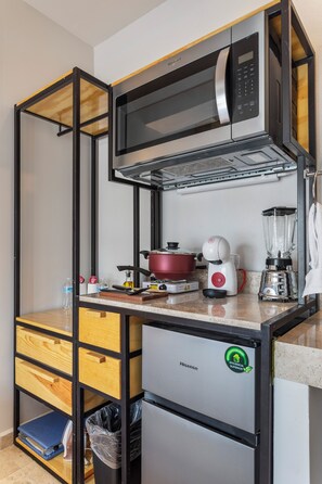 A compact kitchenette with a microwave, a small refrigerator, a blender, and a stove. - Universidad by Homirent (Querétaro)