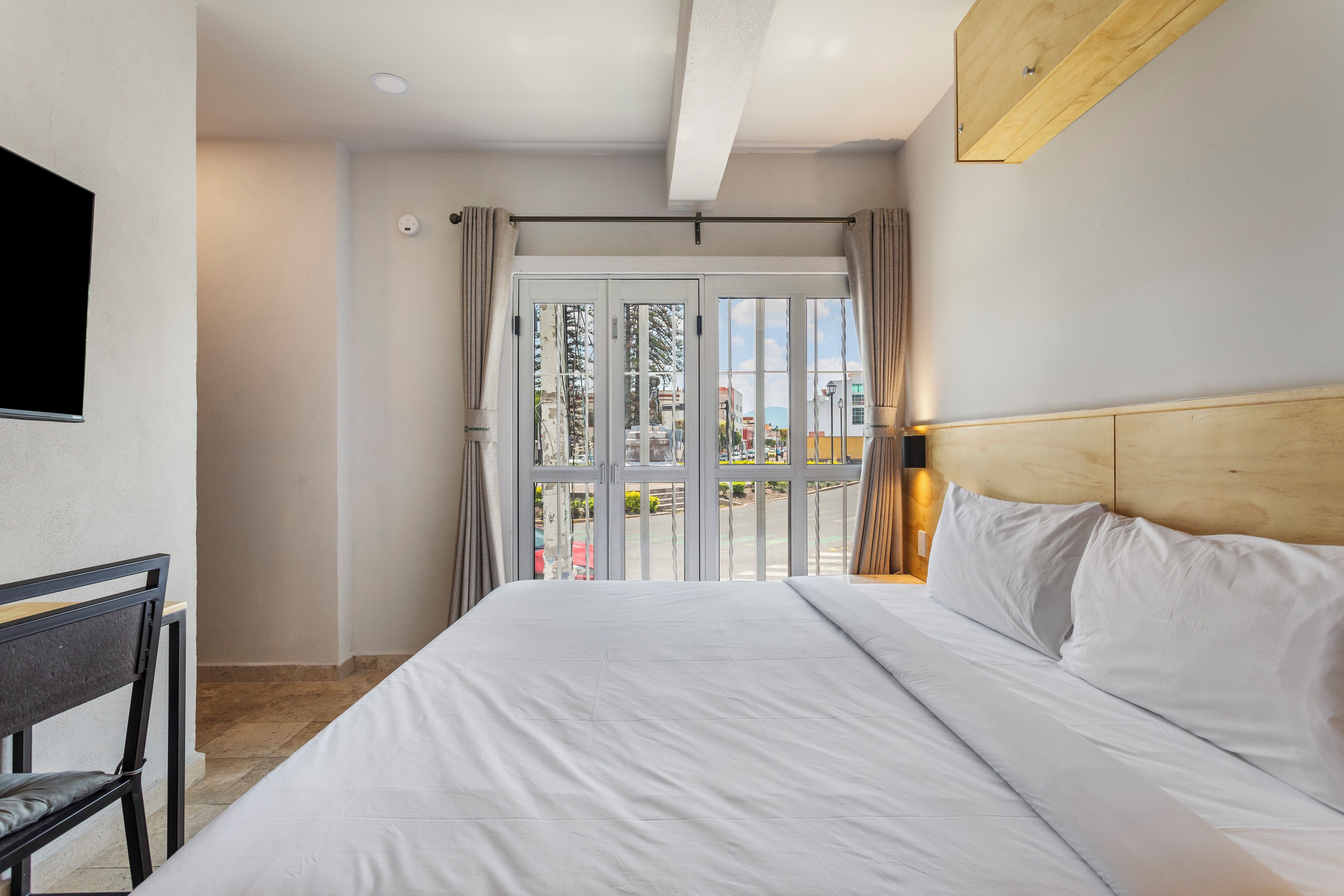 Una habitación de hotel con una cama, un escritorio y vistas al exterior.